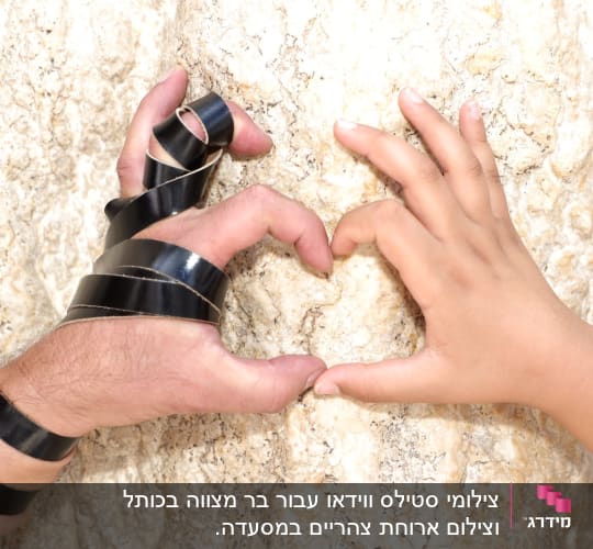 ידיים יוצרות צורת לב על רקע אבן